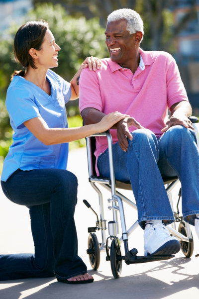 women facing a senior man in a wheelchair with a smile
